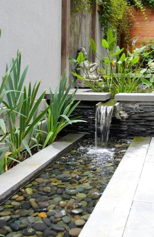 Garden Waterfall flowing into pebbles in tropical pool